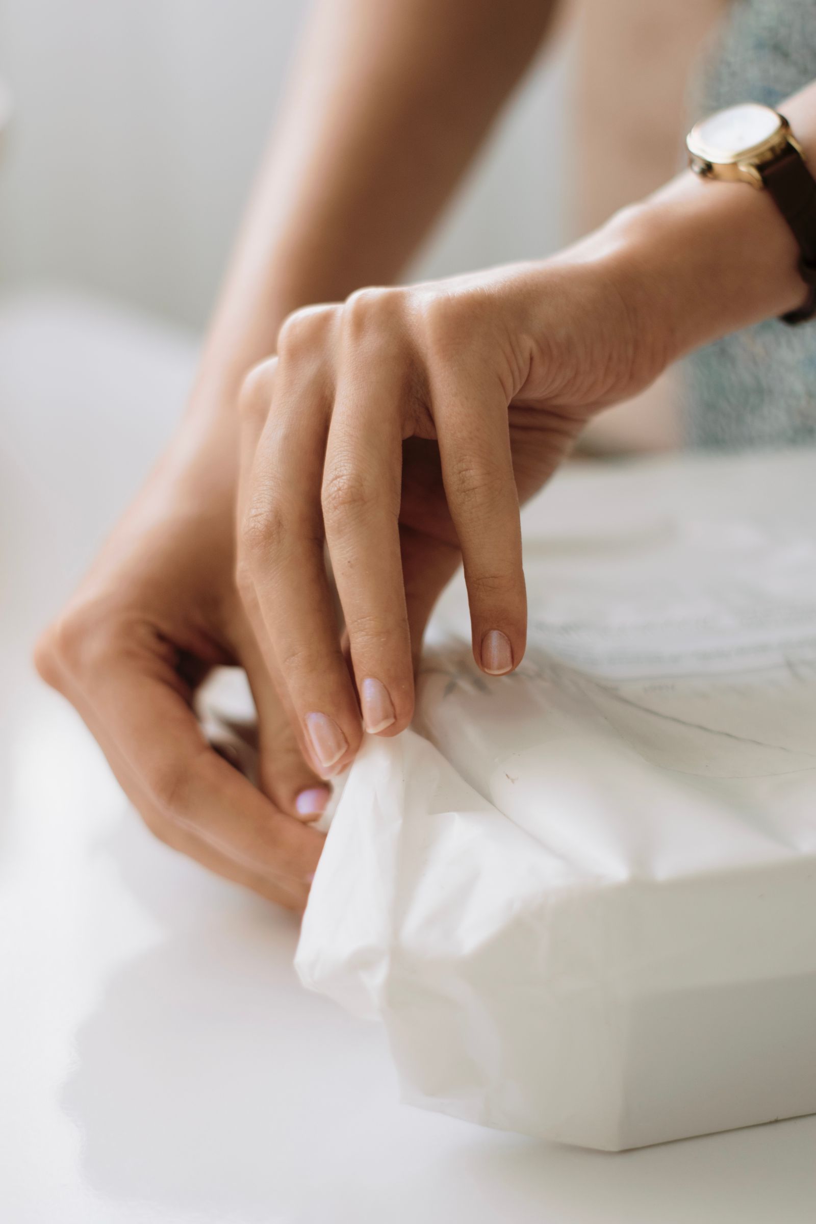 A woman's hands opening a soft sealed package on a white table
